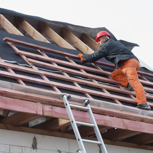 A Roofer Works on an Office Building.