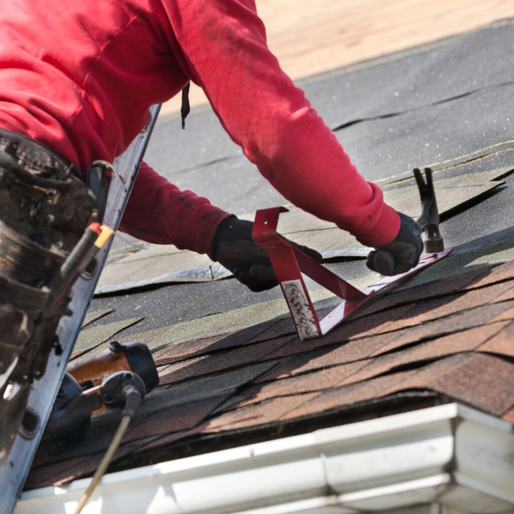 man installing asphalt shingles on residential roof